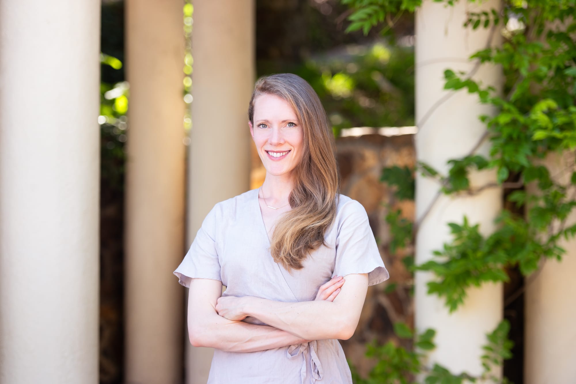 Photo of Liz Fosslien with arms crossed against columns